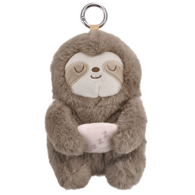 A plush sloth keychain or bag charm in warm taupe-brown and cream, holding a small pink pillow with 'z z z' embroidered, attached to a silver metal ring and tan strap, shown on a plain white background.